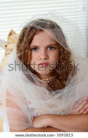 A 10 year old girl playing dress up and looking angry into the camera.