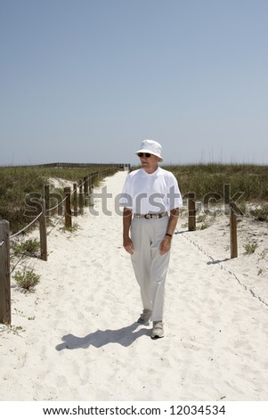 A man walking down a path to the beach.
