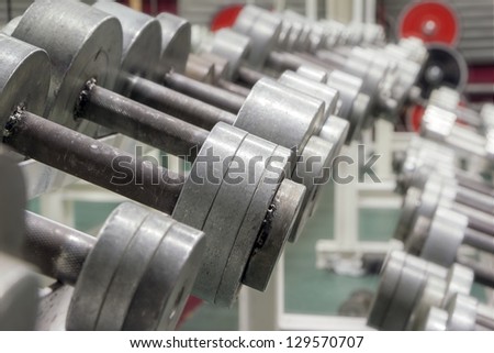 Metal silver dumbbells on an old rusty iron rack