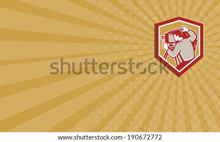Business card illustration of a vintage movie film camera with photographer setting it up set inside shield crest shape done in retro woodcut style.