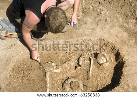Archaeologist excavating a grave buried skeleton