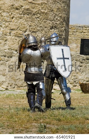 Medieval european knights fighting  near citadel wall