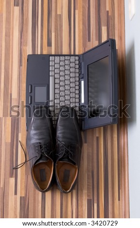 Mans shoes on the notebook, wiev from the top