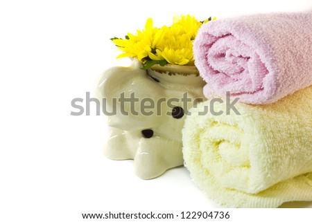 Rolled  towels and a terracotta oil burner with yellow chrysanth