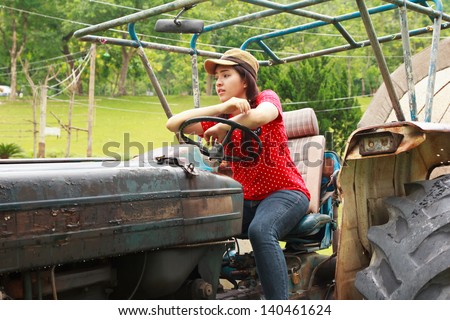 Beautiful woman sitting on tractor on the farm
