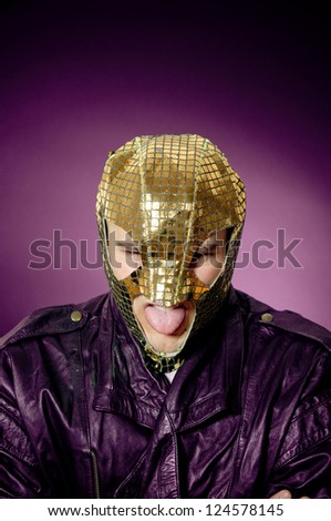 Angry man wearing gold mask. Showing tongue. Queer hero.