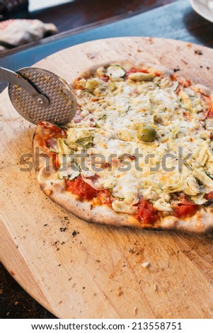 Cutting fresh pizza with pizza cutter