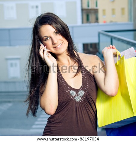 Young woman speaking on the mobile while holding shopping bags