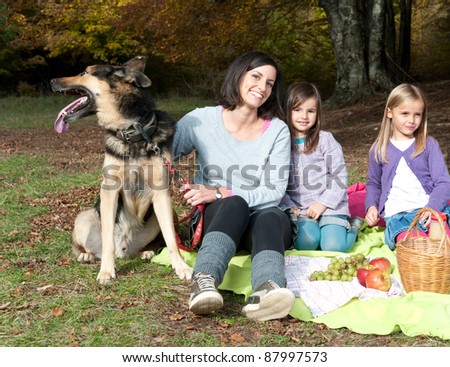 Mother with two daughters and a dog on picnic in forest