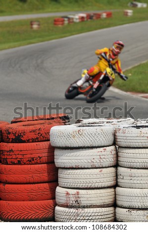 Safety fence with tires on Karting Circuit Francorchamps with motor racer in blur