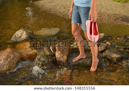 Wading in Creek - Young woman with shoes in hand, cooling off her feet in a creek in the Belgian Ardennes