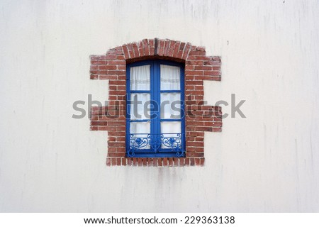 Blue Window metal frame edged with bricks on white House in Brittany, France