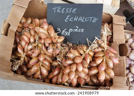 Shallots clusters in a cardboard box as sold on a french market in Brittany, France