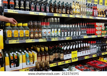 UELSEN, GERMANY - SEPTEMBER 22: Hand takes a bottle from aisle filled with spirits in a Lidl supermarket, their concept is selling mainly house brands, taken on September 22, 2014 in Uelsen, Germany