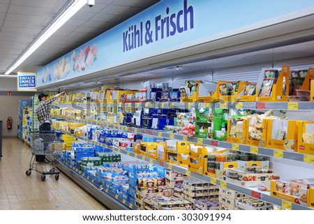 MONSCHAU, GERMANY - JULY 25: Man with a trolley shopping in the refrigerated fresh products aisle of an Aldi supermarket. Aldi is a global discount supermarket chain. Taken on July 25, 2015 in Germany
