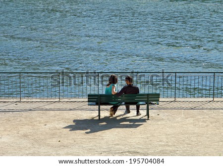 man and woman talking on a bench by the sea
