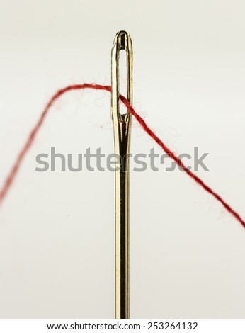 sewing needle and red thread on white background