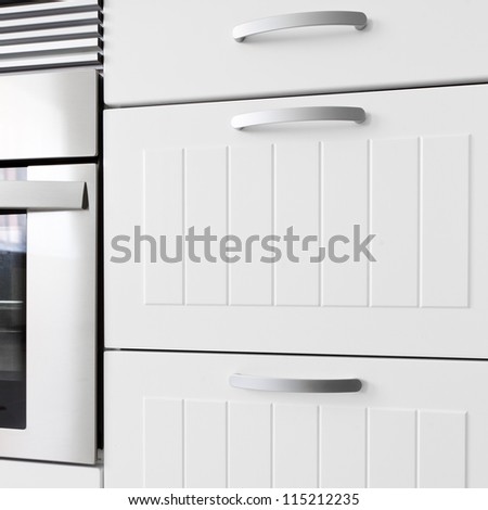 Detail of modern white kitchen. Drawers and oven.