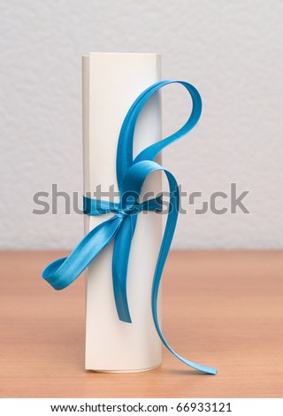 stock photo Paper roll on the wooden table tied with blue ribbon