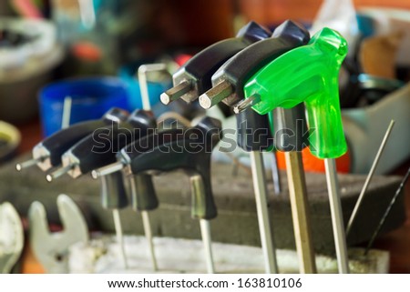 Green screw driver and black screw drivers arranged in bike repair service