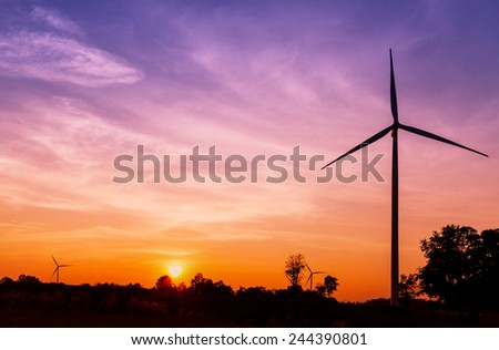 Silhouetted wind turbines power generator on sunset at farmer field