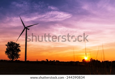Silhouetted wind turbine power generator on sunset at farmer field