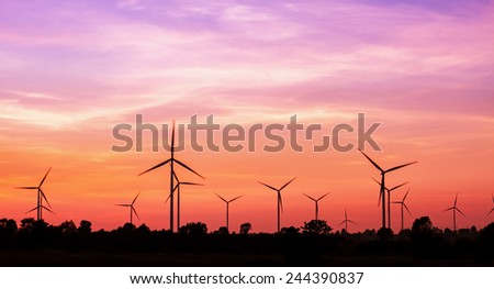 Silhouetted wind turbines power generator on sunset at farmer field