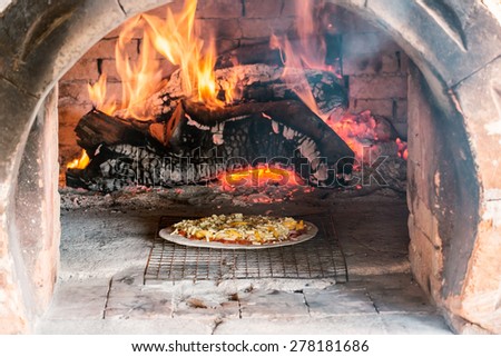 Pizza hawaii cooking in traditional wood fire oven