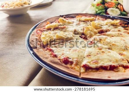 Fresh baked pizza hawaii and sliced on plate