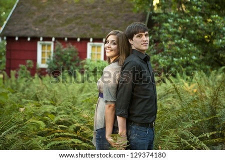 Couple standing back to back among ferns