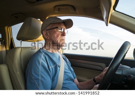 Elderly man driving a car with seat belt on