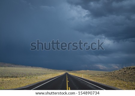 Dark clouds threatening a rain storm above desert highway