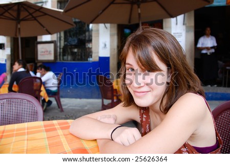 Young woman sitting at a table in an outdoor restaurant in Mexico.