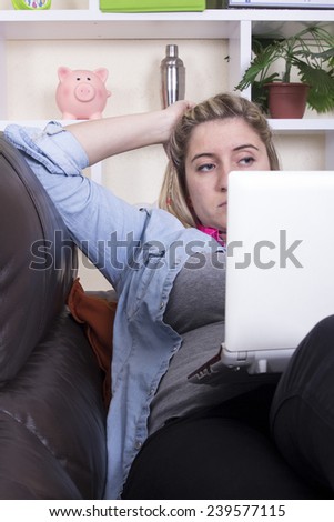 Serious Blonde girl lying on sofa using computer