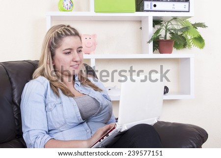 Blonde girl lying on sofa using computer