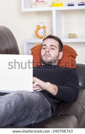 Guy using computer lying on sofa