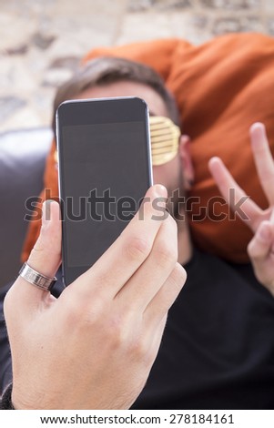 Guy taking selfie with smartphone wearing gold glasses