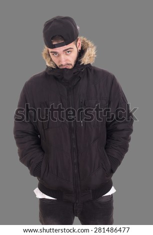 Handsome young guy wearing jacket and black cap with her hands on pockets