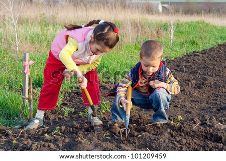 Two little children planting seeds and weed beds in the field