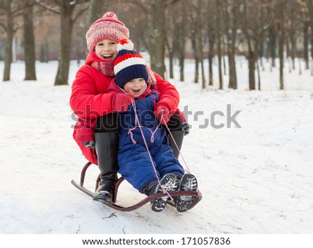 Two happy kids in winter clothes on sled