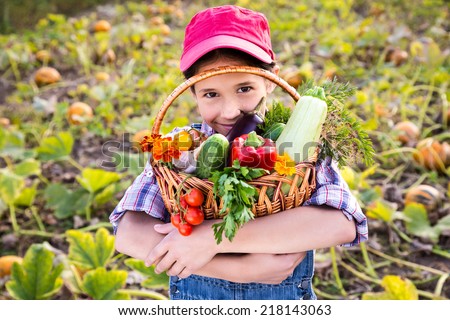 Happy girl on pumpkin's field with basket of vegetables