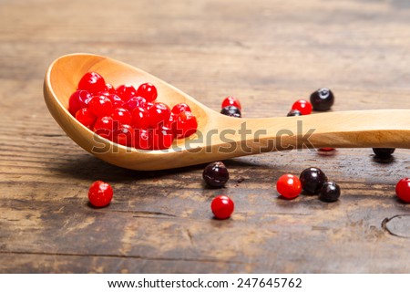 viburnum in wood spoon and black currant on wooden background