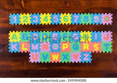 Colorful foam puzzle letters on wooden background, education concept