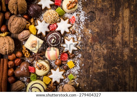 Wooden background with chocolate sweets, candies, nuts, cookies, coffee beans and dried fruits