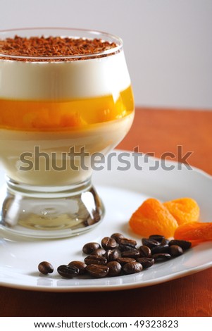 Multilayer gelatin dessert with chocolate, cream and dried apricots jelly in glass