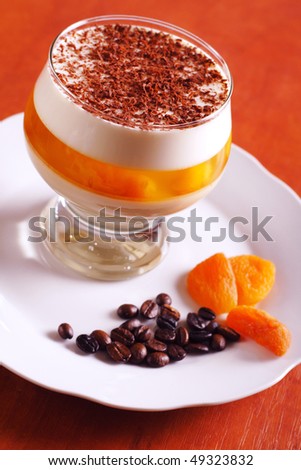 Multilayer gelatin dessert with chocolate, cream and dried apricots jelly in glass