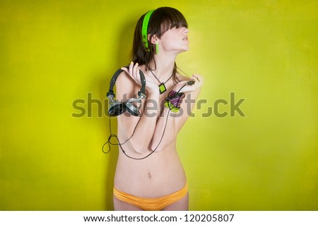 Attractive topless woman with headphones on green background