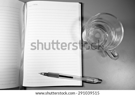 Black and white notebook and pen and empty cup of coffee