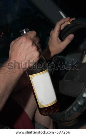 Man sitting in drivers seat of car on rainy night, drinking from a bottle. White space on bottle for text.