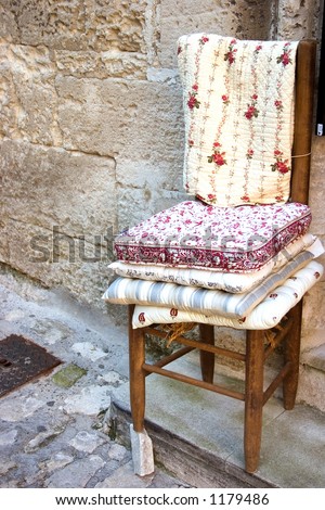 A straight back chair stacked with cushions sits in a village doorway